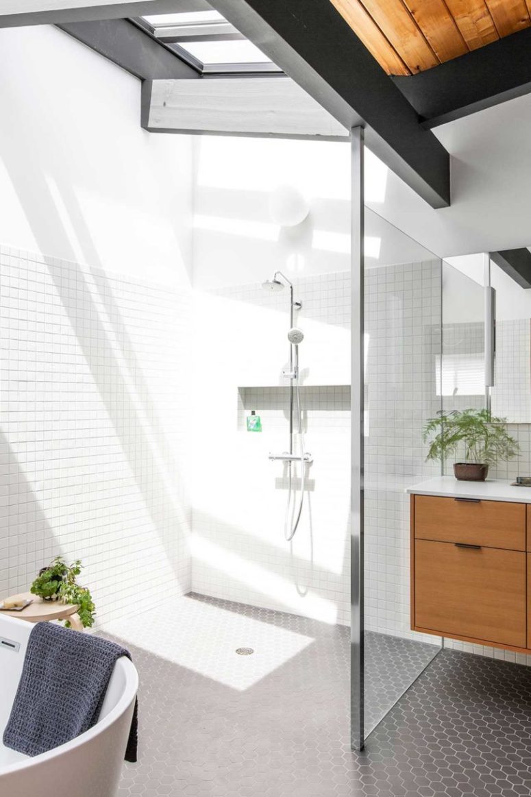 The shower space shows off a skylight, the white tiles reflect it maing this nook sunny