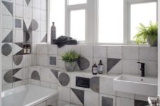 08 This is a black and white bathroom with geometric tiles and a bathtub, there’s a window with frosted glass
