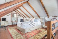 09 The bedroom is done with wooden beams, white shiplap, printed rugs and elegant neutral furniture