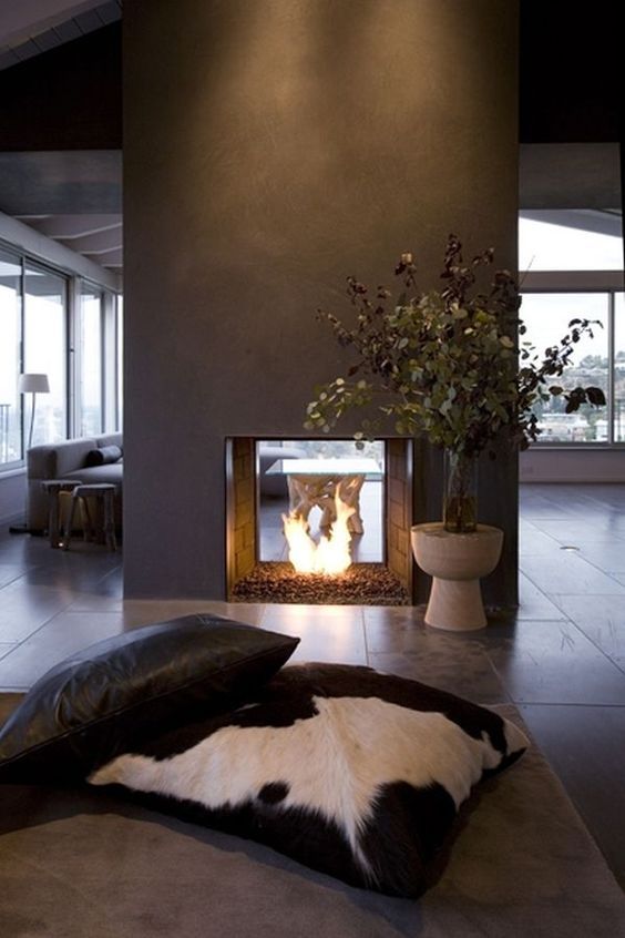 a modern double-sided fireplace done of grey concrete looks really spectacular and very chic