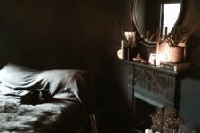 11 a gorgeous dark moody bedroom with a faux fireplace, a dark framed mirror and a bed with black bedding