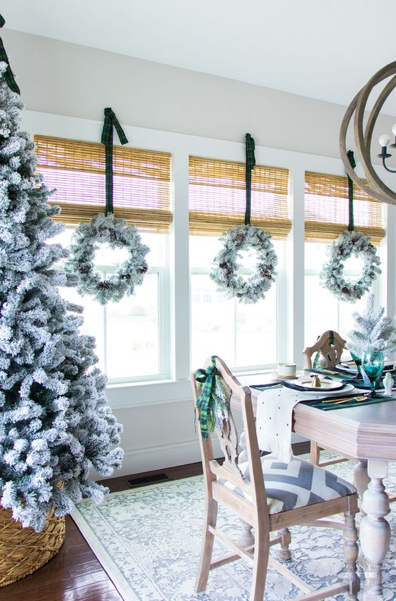 a flocked Christmas tree in a basket, snowy wreaths with pinecones and plaid ribbons snowy posies