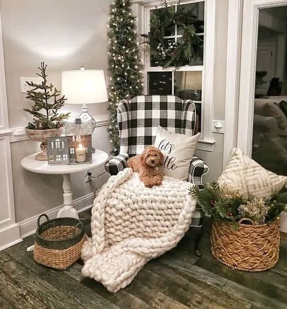 a neutral nook with a chunky knit blanket, evergreens and a Christmas tree with lights, baskets and berries plus a buffalo check chair