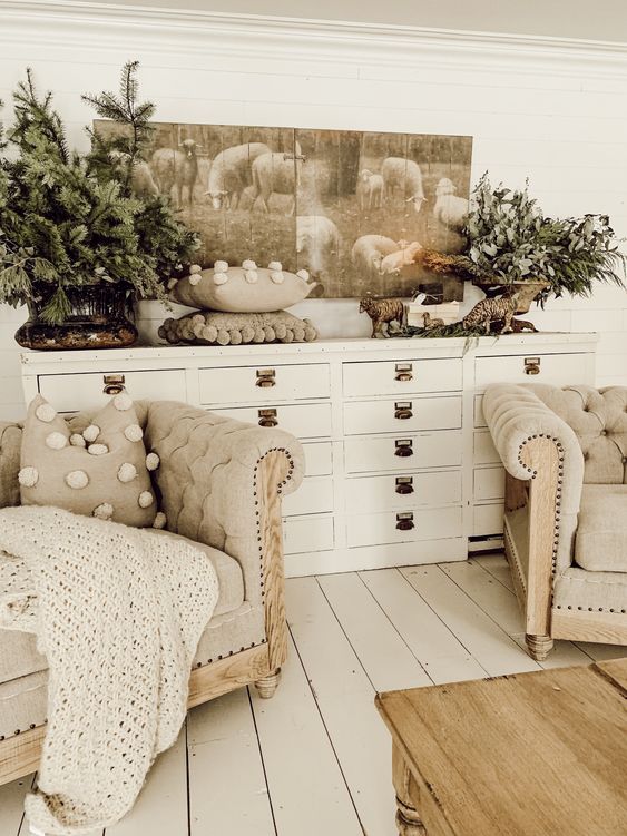 a neutral crochet blanket, pompom pillows, evergreens and greenery in a pot for a chic winter look