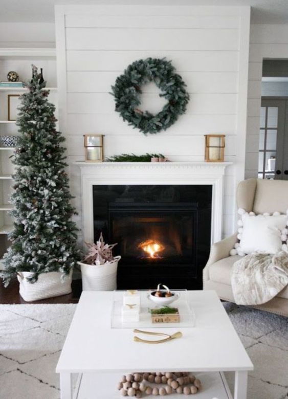 a snowy Christmas tree with pinecones and a matching wreath over the fireplace for clean and natural winter decor