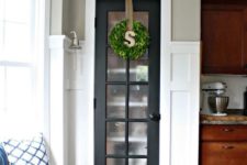 24 a mini built-in pantry with a graphite grey French door and a greenery wreath for a farmhouse kitchen