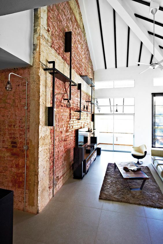 a brick wall and exposed black pipes make the space feel industrial and add interest to it