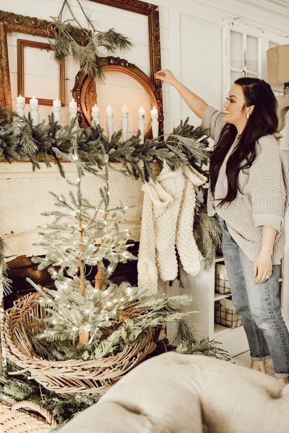 elegant frames, candles in wooden candleholders, evergreen garlands and a Christmas tree with lights in basket