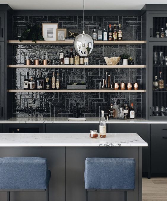 a black kitchen with a glossy black tile backsplash, open shelves, a grey kitchen island and navy stools is cool and chic