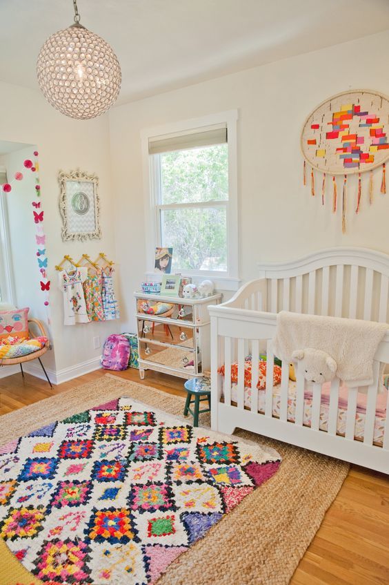a bright and fun nursery with a colroful rug, bedding, an embroidery hoop with tassels and colorful butterflies