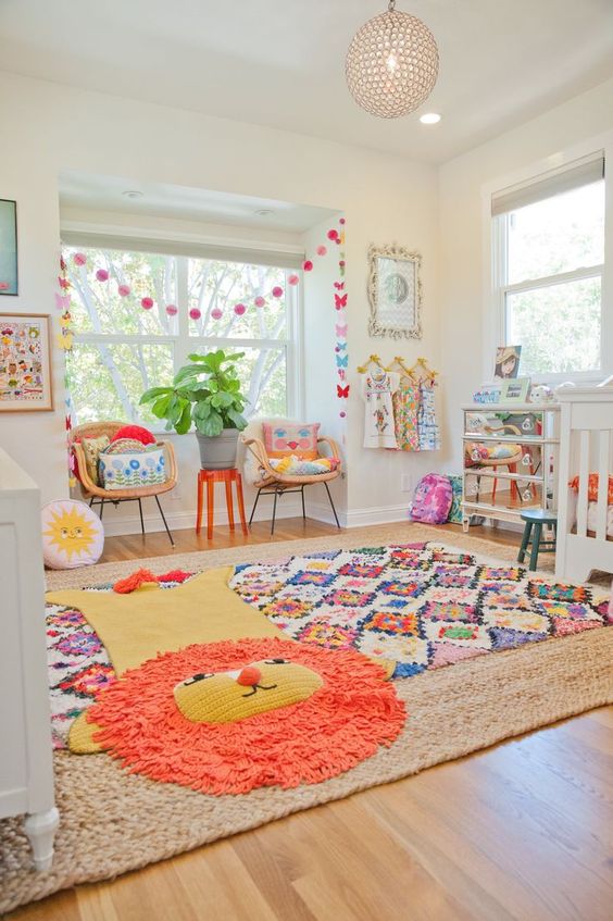 a bright nursery with layered colorful rugs, bright bedding and pillows, bright garlands and toys