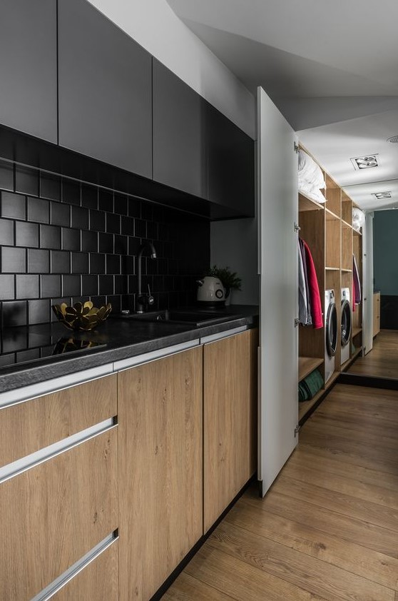 a minimalist kitchen with stained and black cabients, a matte black square tile backsplash and black countertops looks chic