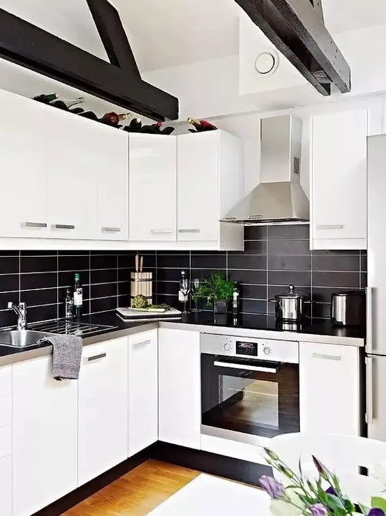 a modern contrasting kitchen with white cabinets, a black stacked tile backsplash and metal countertops is extra bold