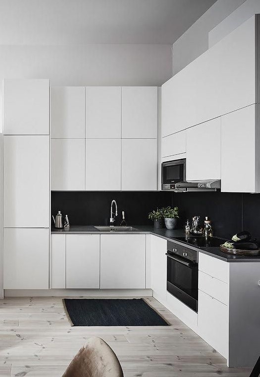 a sleek white kitchen with black large scale tile backsplash that contrasts and stands out a lot