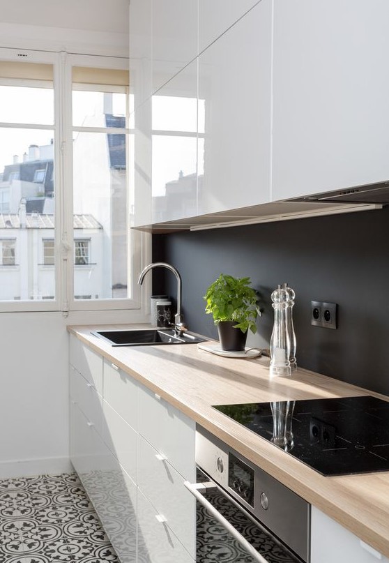 a sleek white kitchen with butcherblock countertops and a chalkboard backsplash to create a contrast here