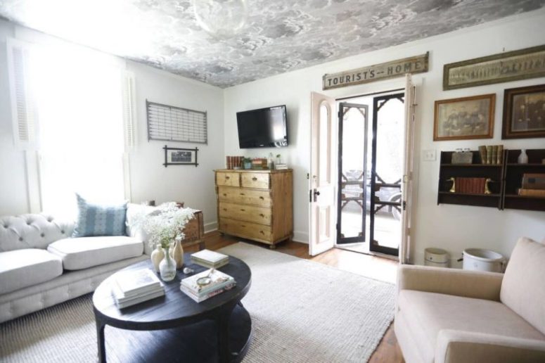 The living room features neutral furniture, some shabby chic items, a printed ceiling and some black touches for drama