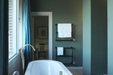 05 The bathroom is done in blue, with vintage details and a large oval bathtub plus gold touches