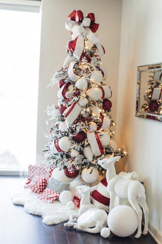 a chic flocked Christmas tree with lights, oversized red and white ornaments and matching ribbons plus a bow on top