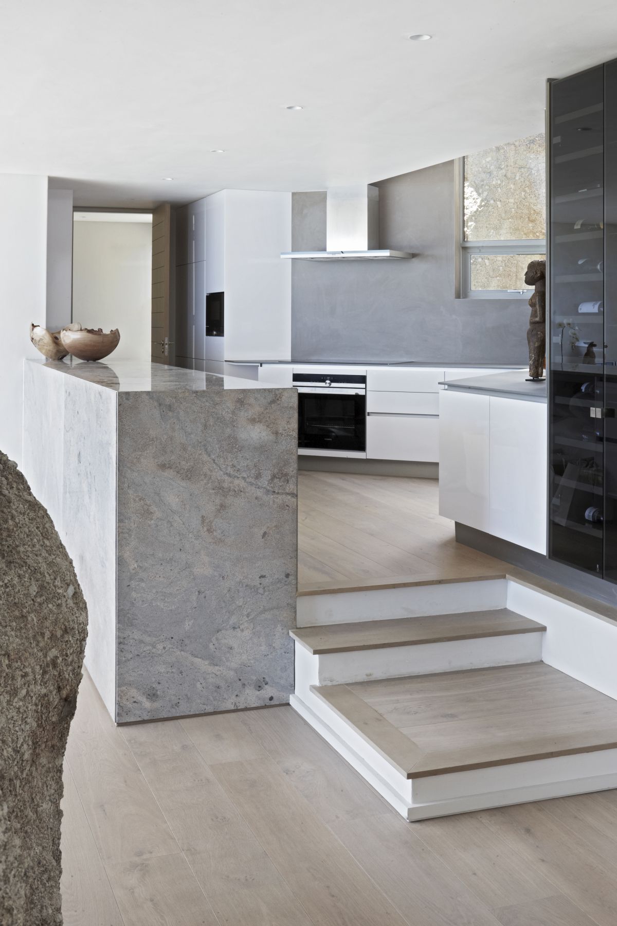 The kitchen is done in white and grey, the kitchen island is done in stone and there are cool views
