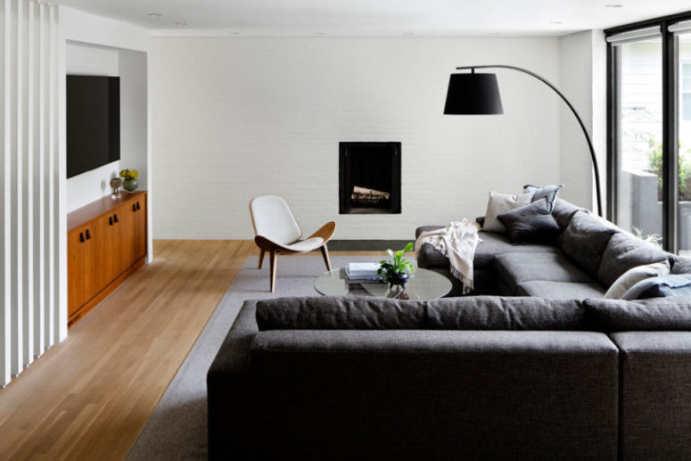 The living room is done with a corner sofa, a TV, a built in fireplace and md century modern furniture The living room is done with a corner sofa, a TV, a built-in fireplace and md-century modern furniture
