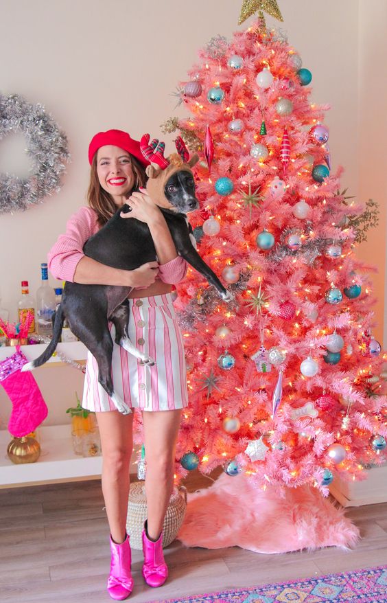 a bright pink Christmas tree with colorful and pastel ornaments, lights and a gold star tree topper