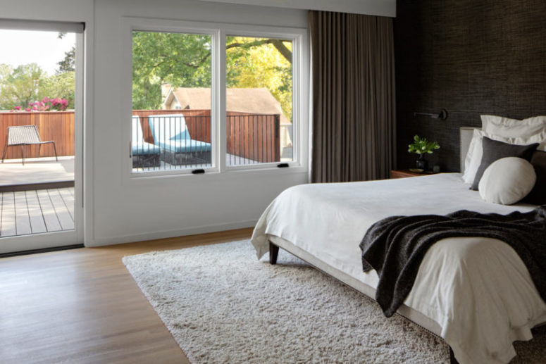 The bedroom is done with a black wall, a monochromatic bed and textiles, there's an entrance to a terrace The bedroom is done with a black wall, a monochromatic bed and textiles, there's an entrance to a terrace