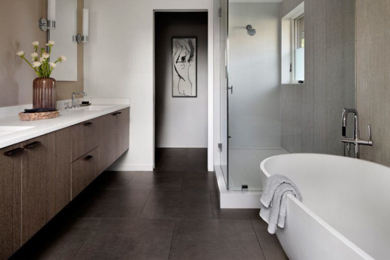 The bathroom features a large floating vanity, a shower space and an oval tub
