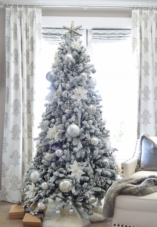 a flocked Christmas tree with silver and silver glitter usual and oversized Christmas ornaments looks frozen