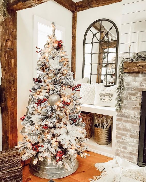 a flocked farmhouse Christmas tree with red berries, metallic ornaments including large ones and fabric blooms