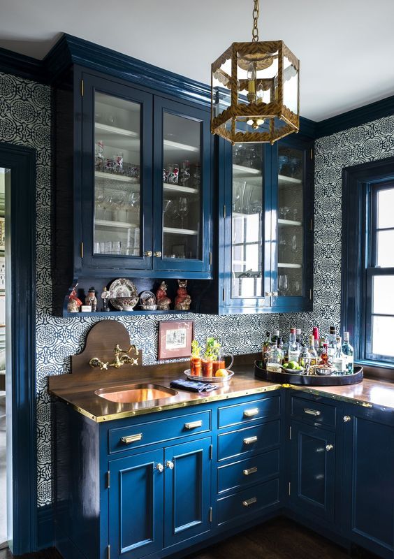 a vintage classic blue kitchen with wooden countertops and printed wallpaper is a chic and cool space with a fashionable touch