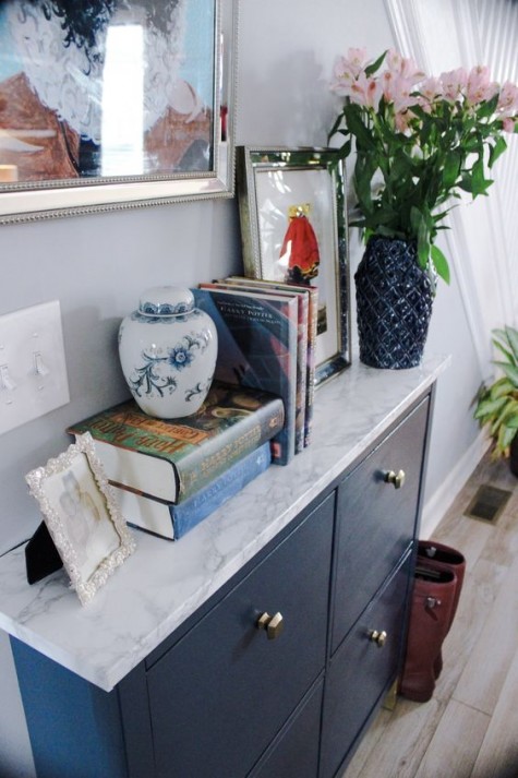 a navy IKEA Hemnes shoe cabinet with navy paint and some marble contact paper plus brass knobs to get a stylish look