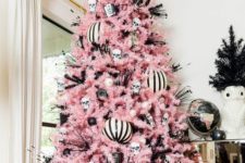 16 a pastel pink Christmas tree with black and white ornaments, skulls, witches’ legs and a vintage cameras for a Halloween-inspired tree