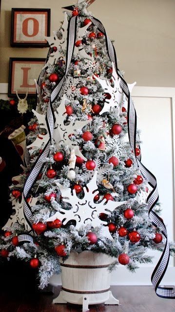 a flocked Christmas tree with checked ribbons, red ornaments and oversized plywood ornaments