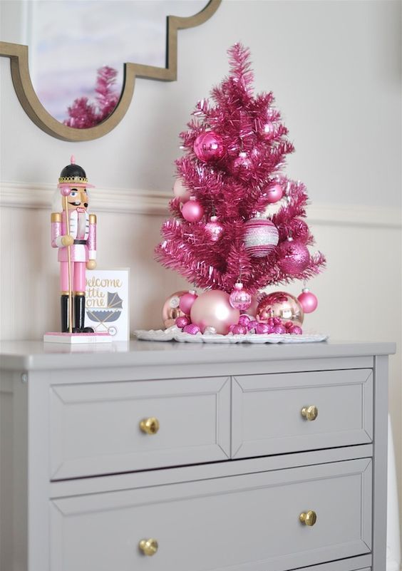 a tiny hot pink tinsel Christmas tree with bright pink glitter ornaments is a nice tabletop version of a usual one