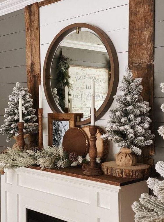 a rustic Christmas mantel with flocked Christmas trees, wood slices, evergreens and candles in wooden candleholders