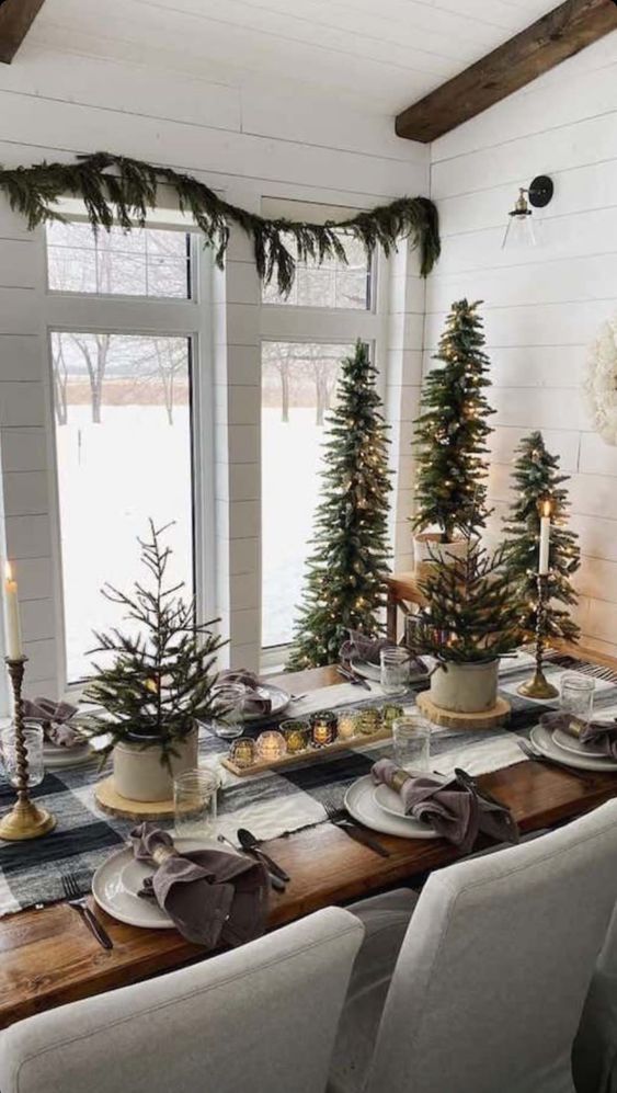 a rustic Christmas table setting with potted Christmas trees, candles and plaid linens is amazing