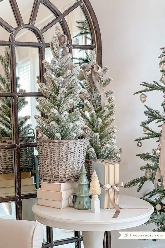 a small tabletop Christmas tree display of flocked trees in baskets, with books and faux trees is a cool farmhouse holiday decor idea