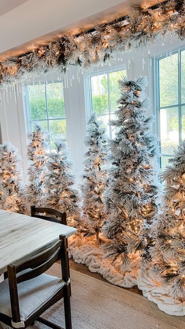 multiple Christmas trees with lights only and a matching overhead garland over them are amazing for holiday styling