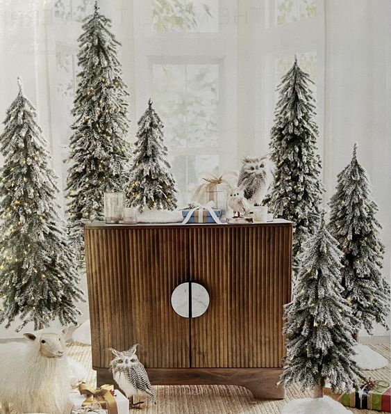 multiple flocked Christmas trees and some faux owls will turn your entryway into a snowy fairy-tale