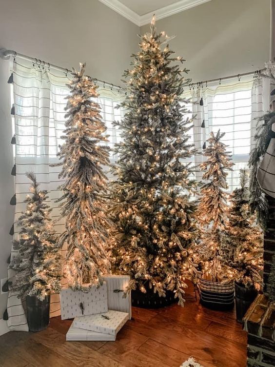 multiple flocked holiday trees in baskets, with only lights as decor, are adorable for cozy farmhouse Christmas decor