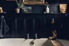 04 a moody vintage-inspired bathroom with black walls, a dark bathtub and a shelf with lots of plants