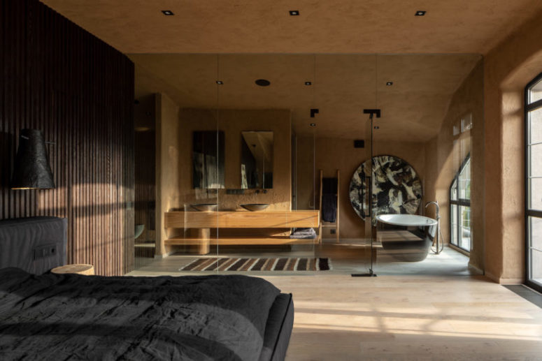 The dark part is compensated with a light filled part an ocher bathroom with stone walls separated with a glass wall The dark part is compensated with a light-filled part - an ocher bathroom with stone walls separated with a glass wall