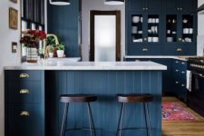 05 a chic navy kitchen with white stone countertops, dark wooden beams and chairs for a contrast