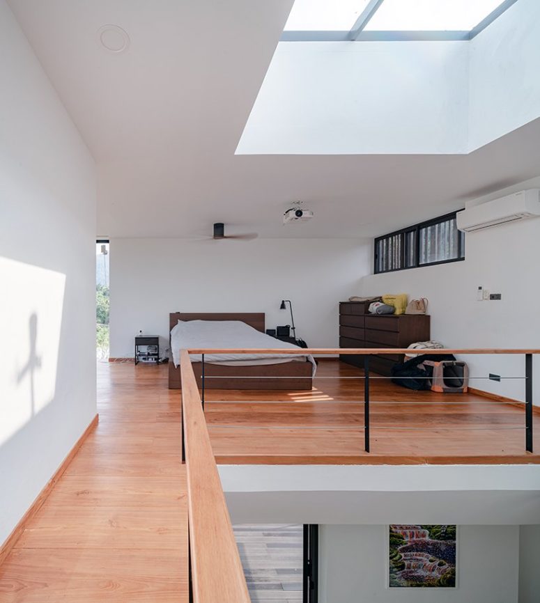 The bedroom features some dark stained furniture, lamps and a large skylight that brings much light in