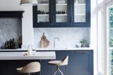 06 a bold navy kitchen with white countertops and a stone backsplash and pendant lamps is super chic