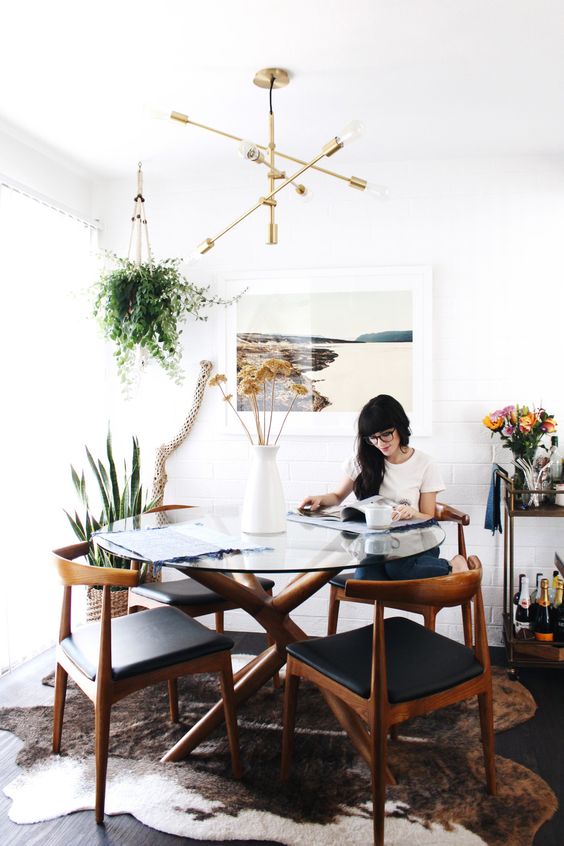 a mid-century modern dining space with a glass round table and chic leather chairs plus rich-stained wood