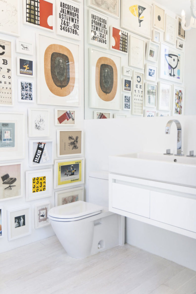 The powder room is done with a colorful gallery wall, sleke white appliances and a large mirror