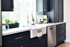 07 a stylish navy kitchen with gold fixtures and handles, a white countertop and chic lamps