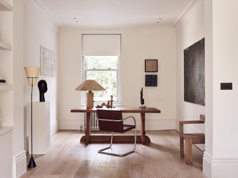 The home office features a chic wooden desk and a leather chair plus some art