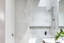 09 a chic and clean minimalist bathroom done with white marble tiles and a skylight to make the space more welcoming